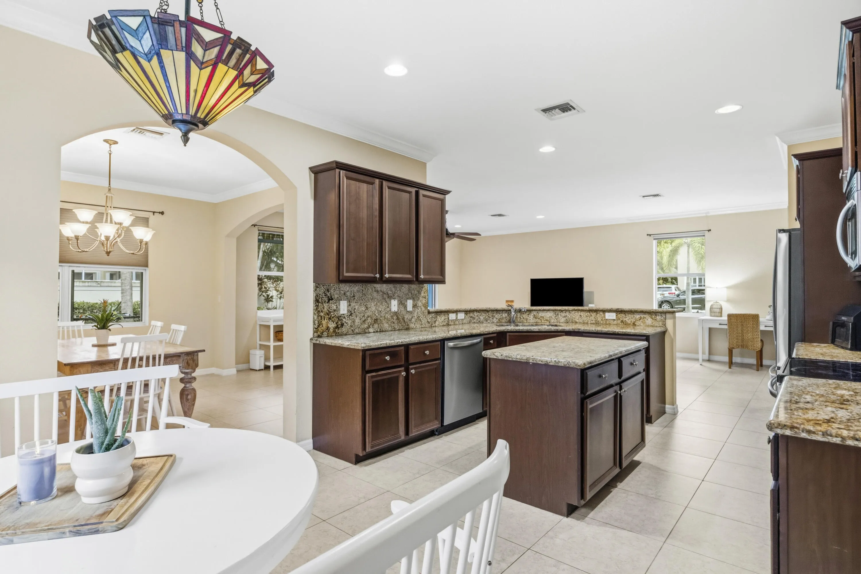 Kitchen featuring wood-finish cabinetry, stone countertops, stainless steel appliances, and a central island