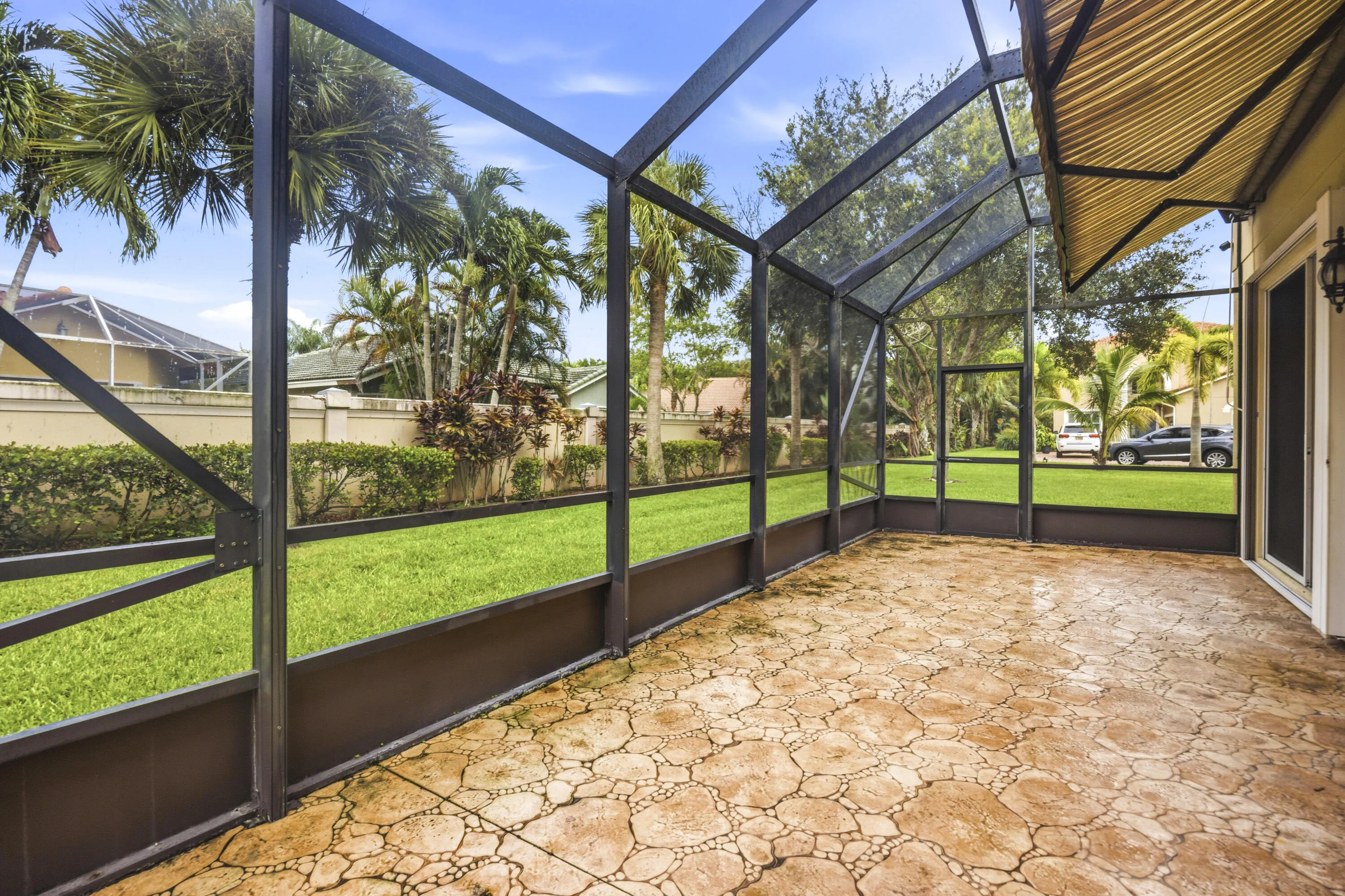 Screened outdoor patio featuring a patterned stone-finish floor and an awning