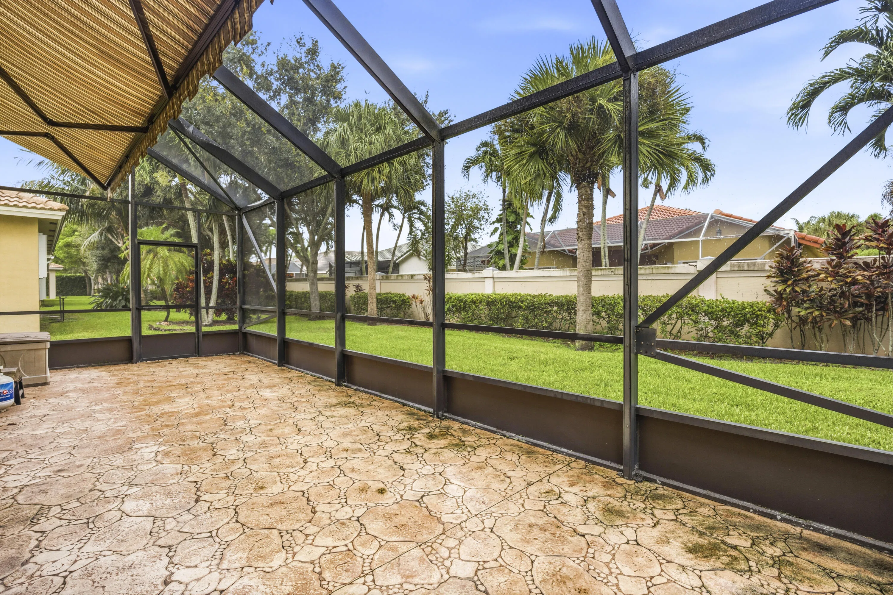 Screened patio with patterned concrete flooring, overhead awning, and open-air enclosure