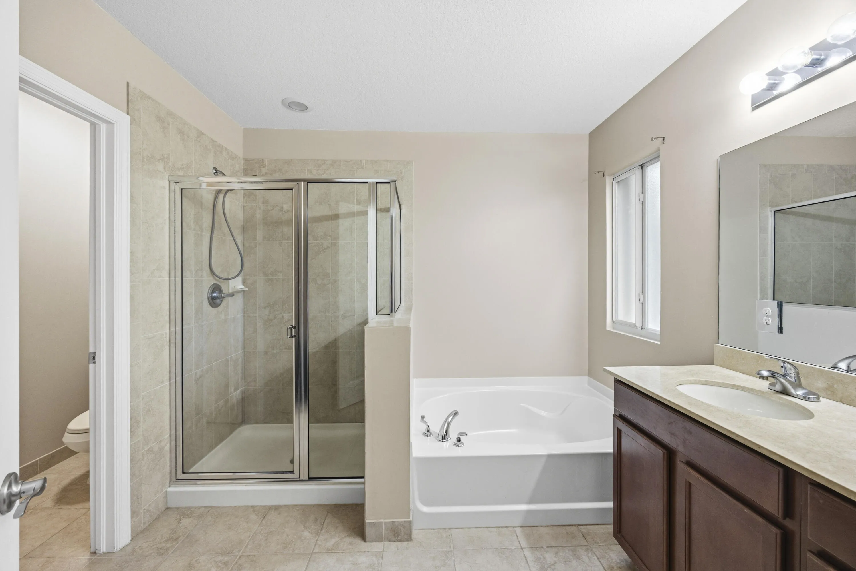 Bathroom featuring a glass-enclosed shower, a built-in tub, a single vanity with a countertop, and tiled flooring
