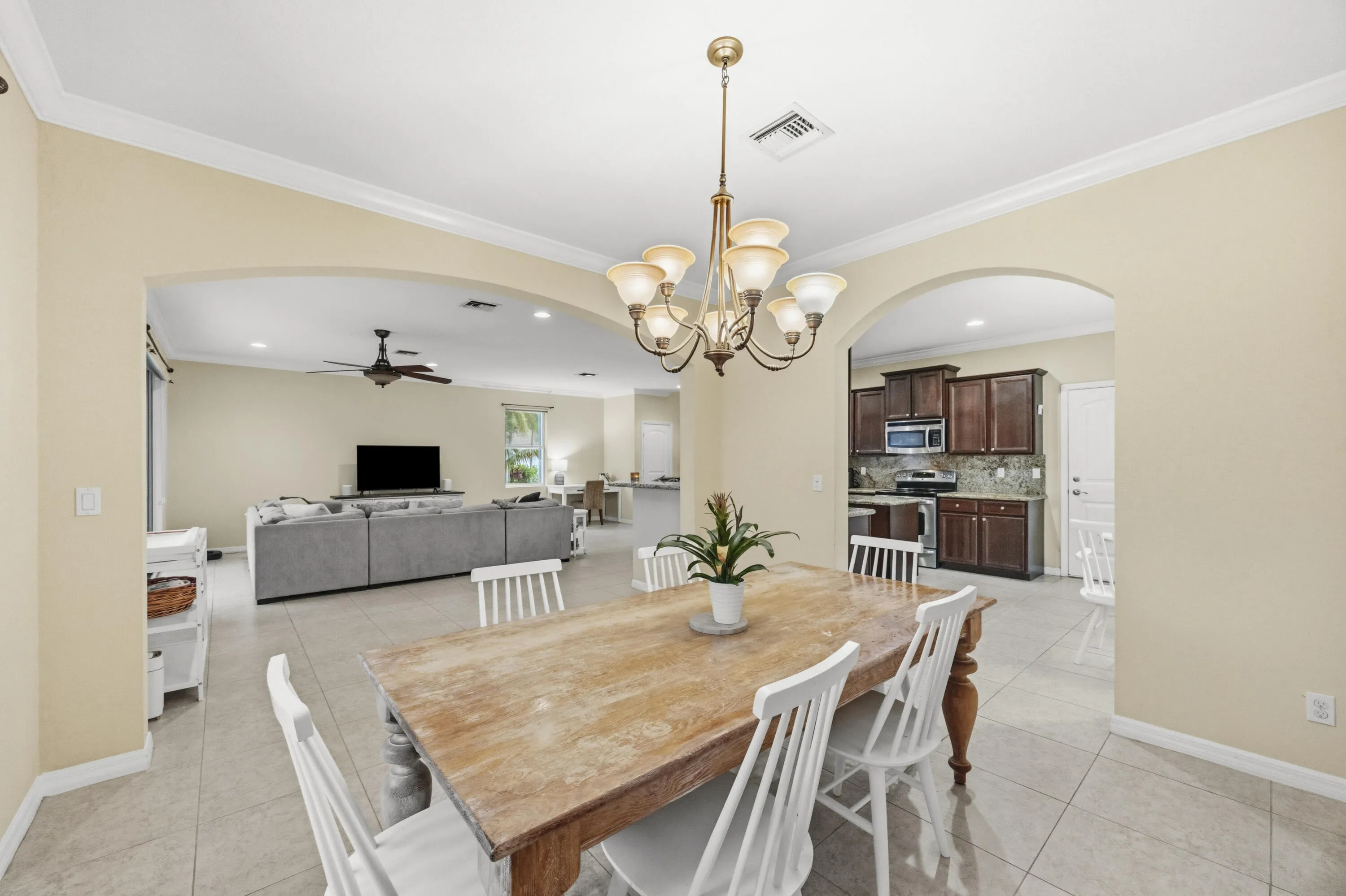 Tiled flooring throughout, crown molding, arched doorways, and a chandelier lighting fixture