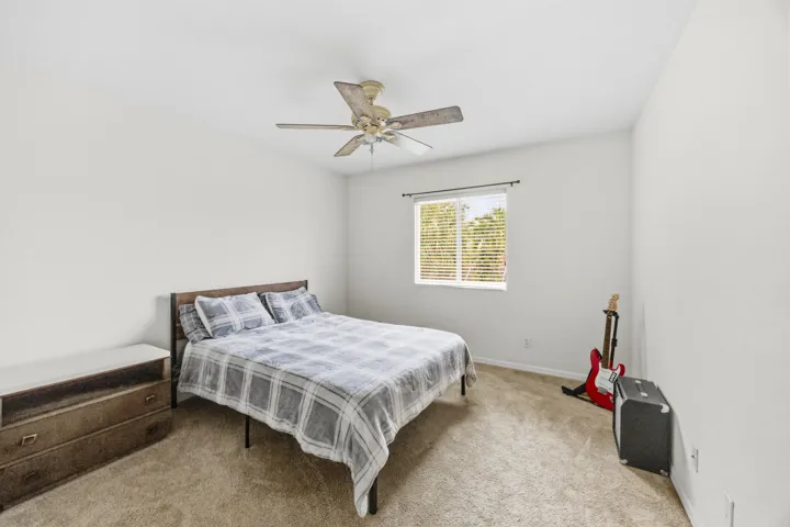Carpeted room with a ceiling fan, a single window with blinds, and white walls