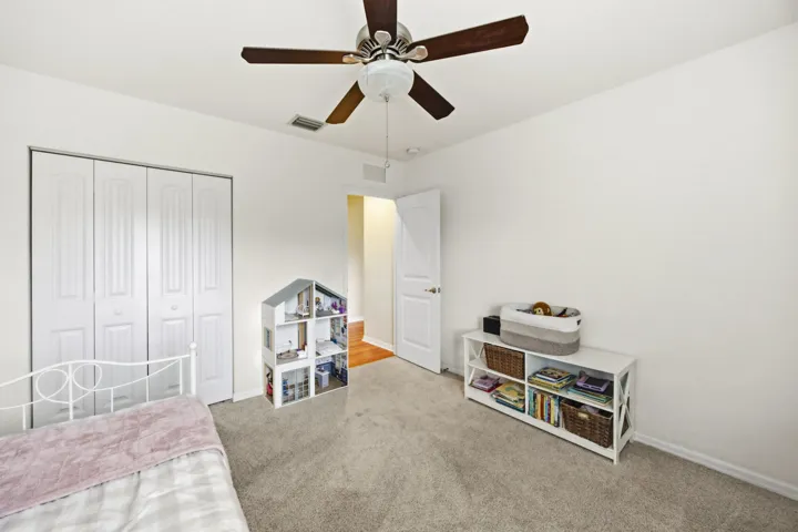 Neutral wall paint, carpet flooring, and a ceiling fan with light fixture
