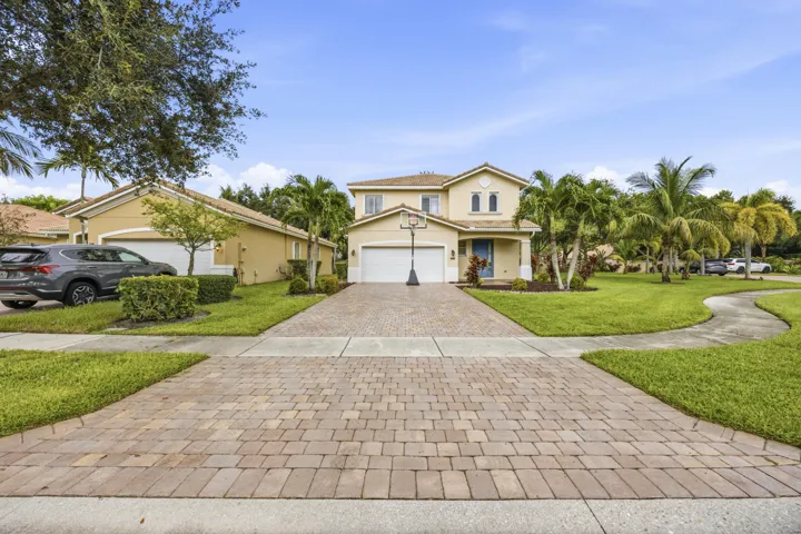 Paved brick driveway leading to a two-story residence with a two-car garage