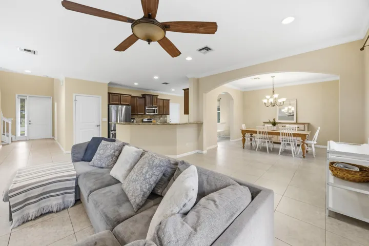 Open-concept living area with tile flooring throughout, featuring an arched doorway, recessed lighting, and a ceiling fan