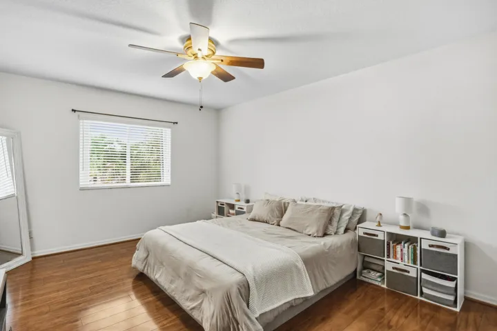 Wood-finish flooring, white walls, window with blinds, and a ceiling fan