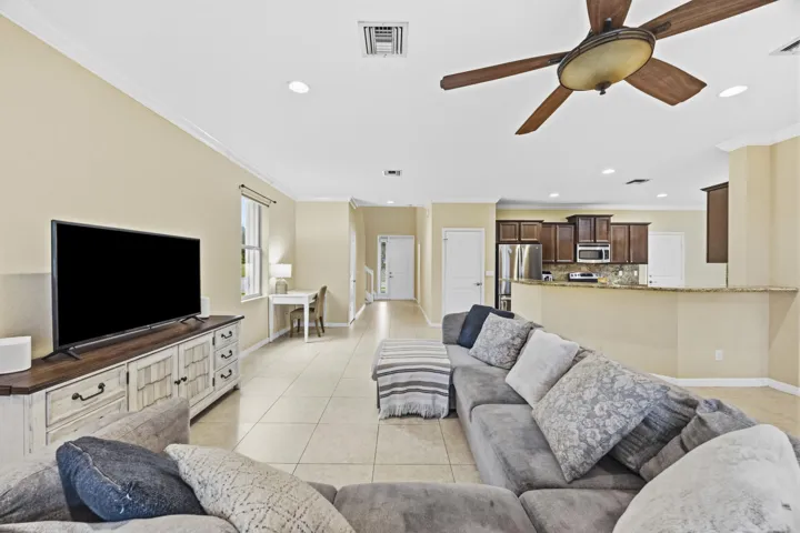 Spacious open-concept living area with tile flooring, crown molding, and recessed lighting