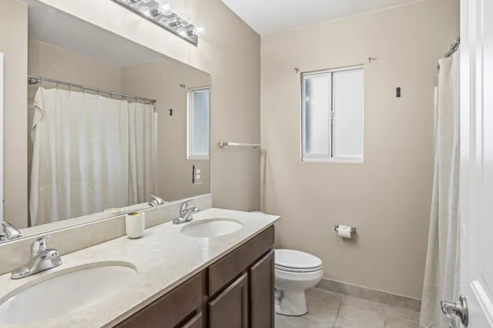 Dual vanity with integrated sinks, light-toned countertop, and dark wood-finish cabinetry