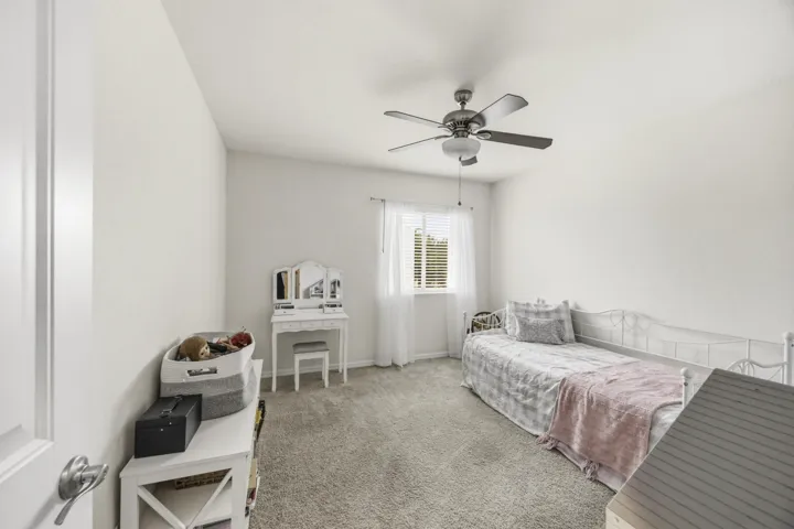 Carpeted flooring, window with blinds, ceiling fan with light, and light-toned walls