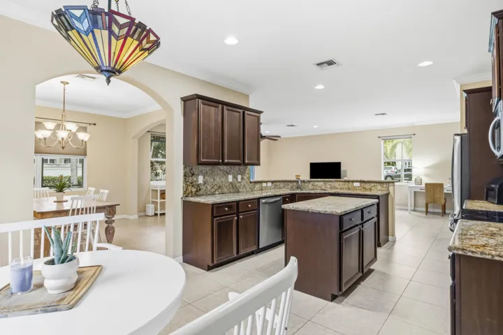 Kitchen featuring wood-finish cabinetry, stone countertops, stainless steel appliances, and a central island