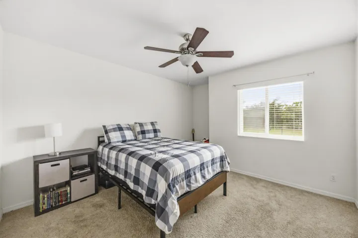 Neutral wall color, carpet flooring, a ceiling fan with light, and a window with blinds