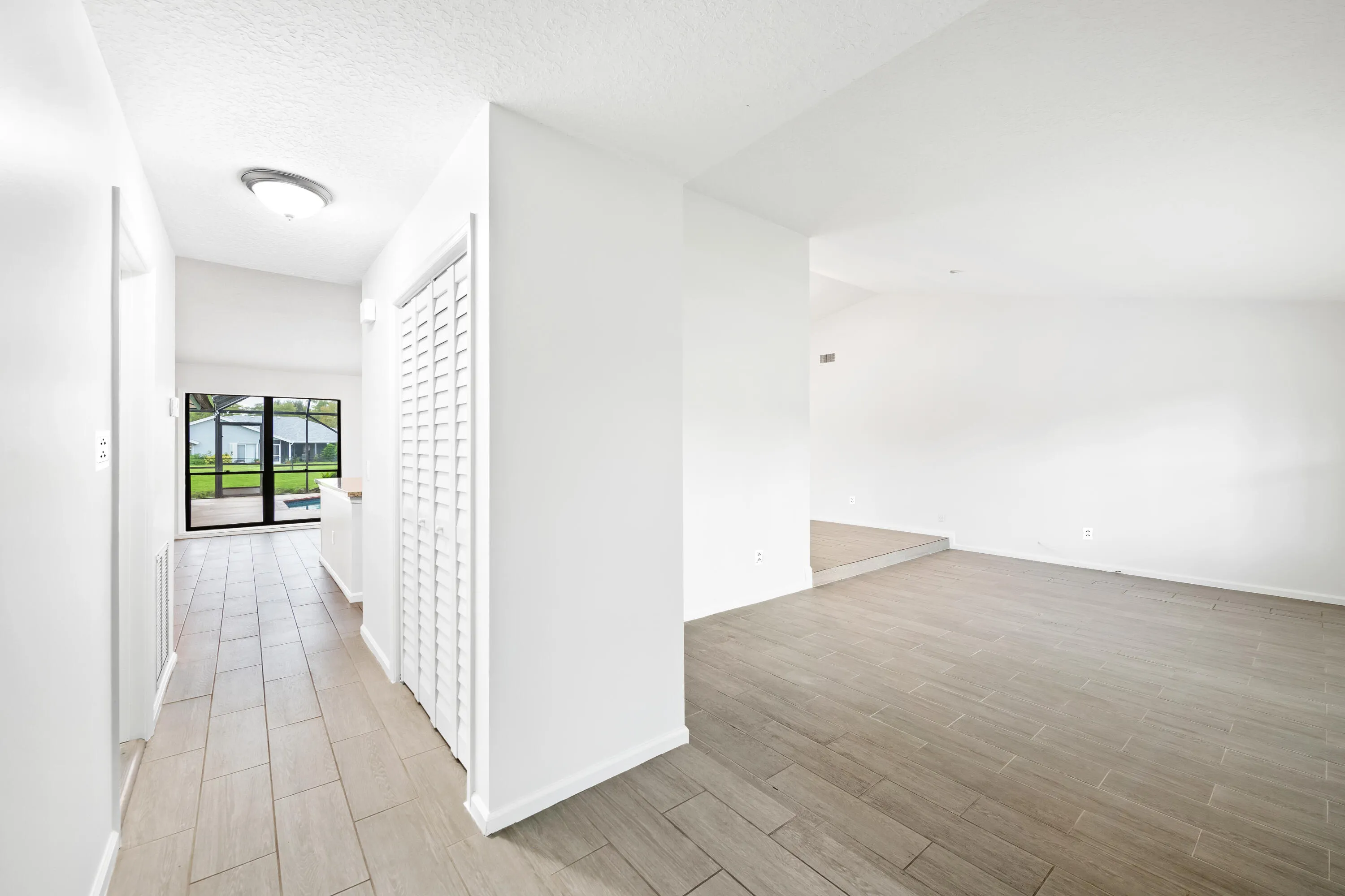 White painted walls with tile flooring, louvered bi-fold door, and a vaulted ceiling