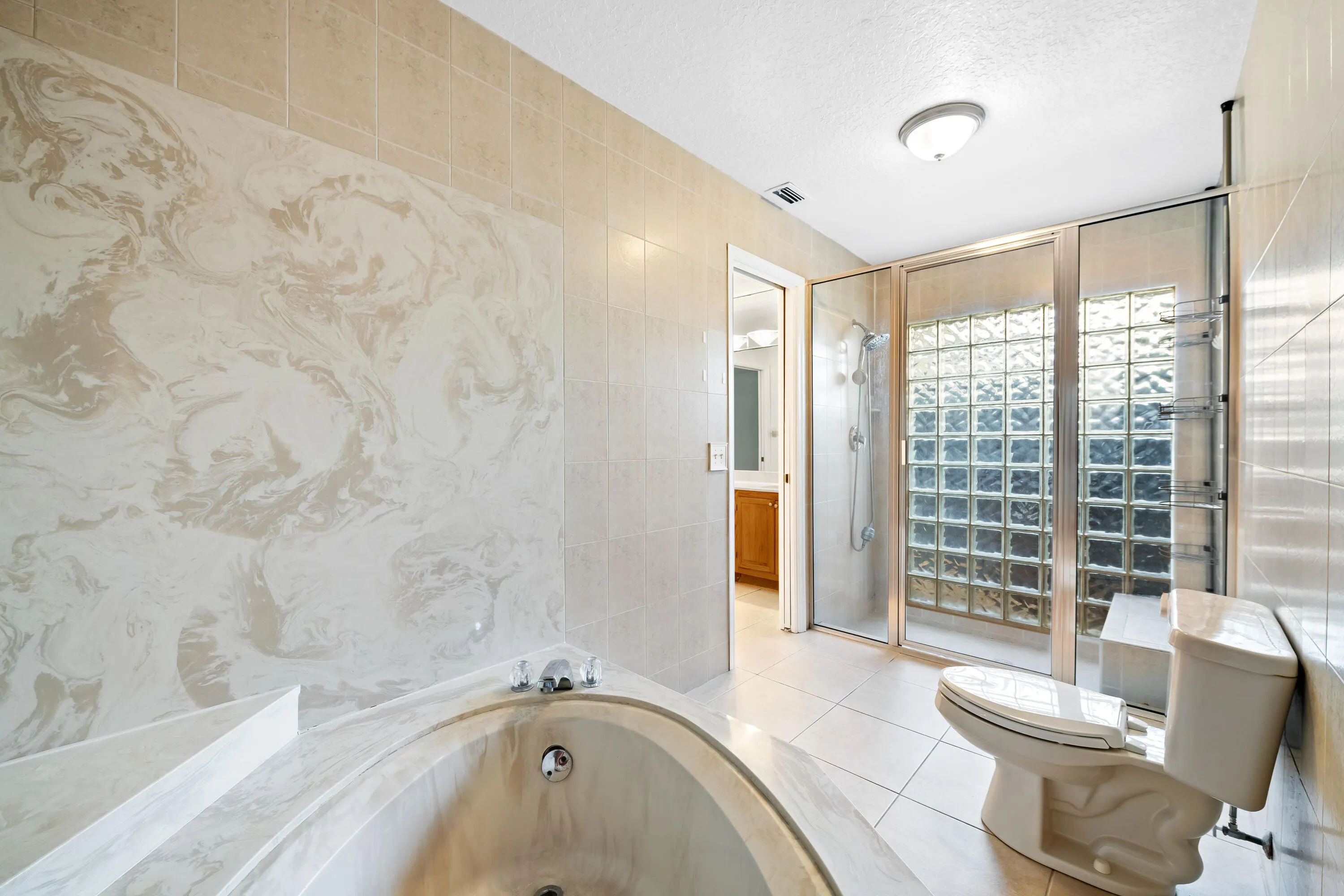 Built-in soaking tub with a tiled surround, glass block shower enclosure, tiled flooring, and a flush-mount ceiling light fixture