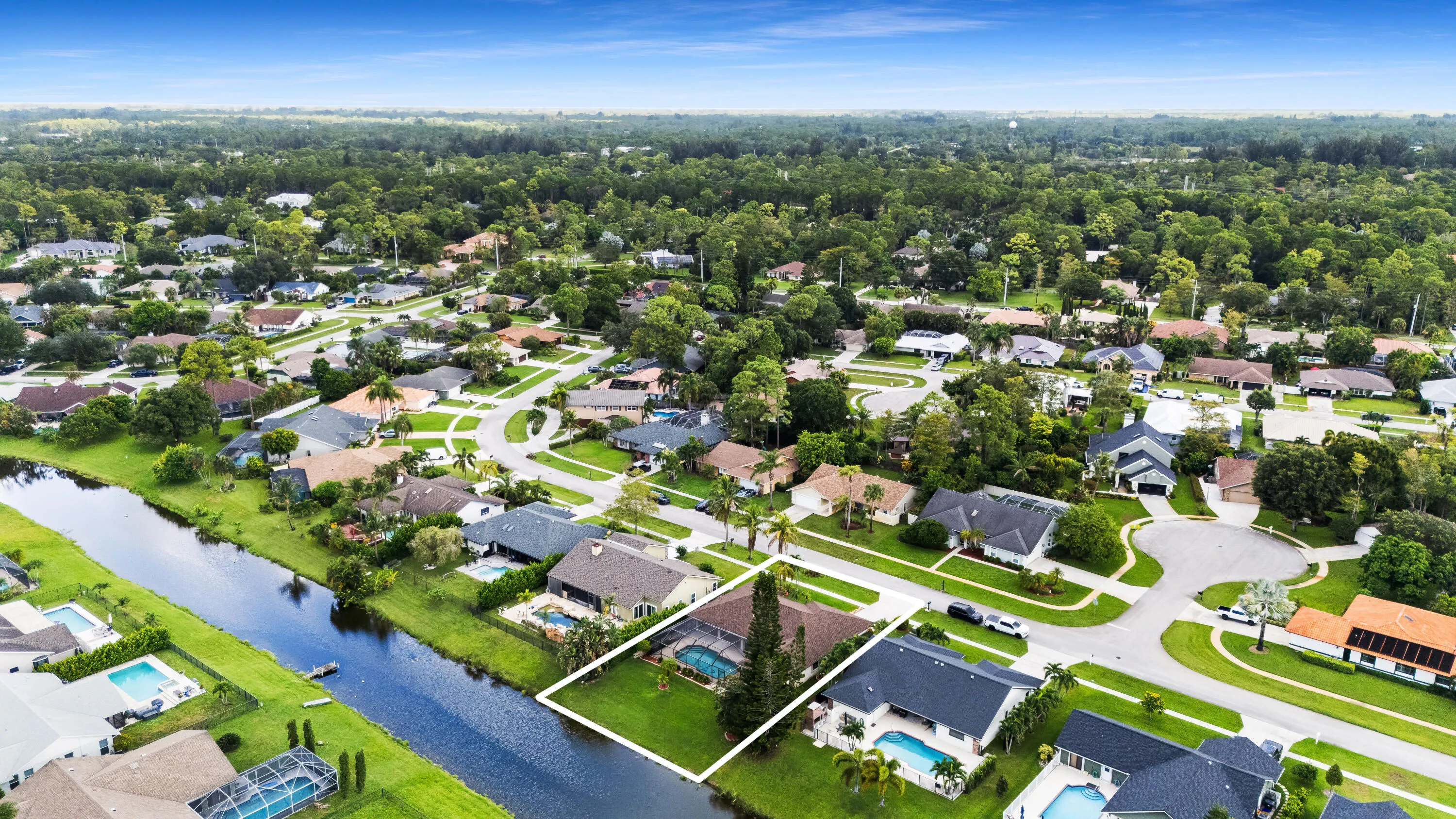 Canal-front property featuring a private pool and mature landscaping