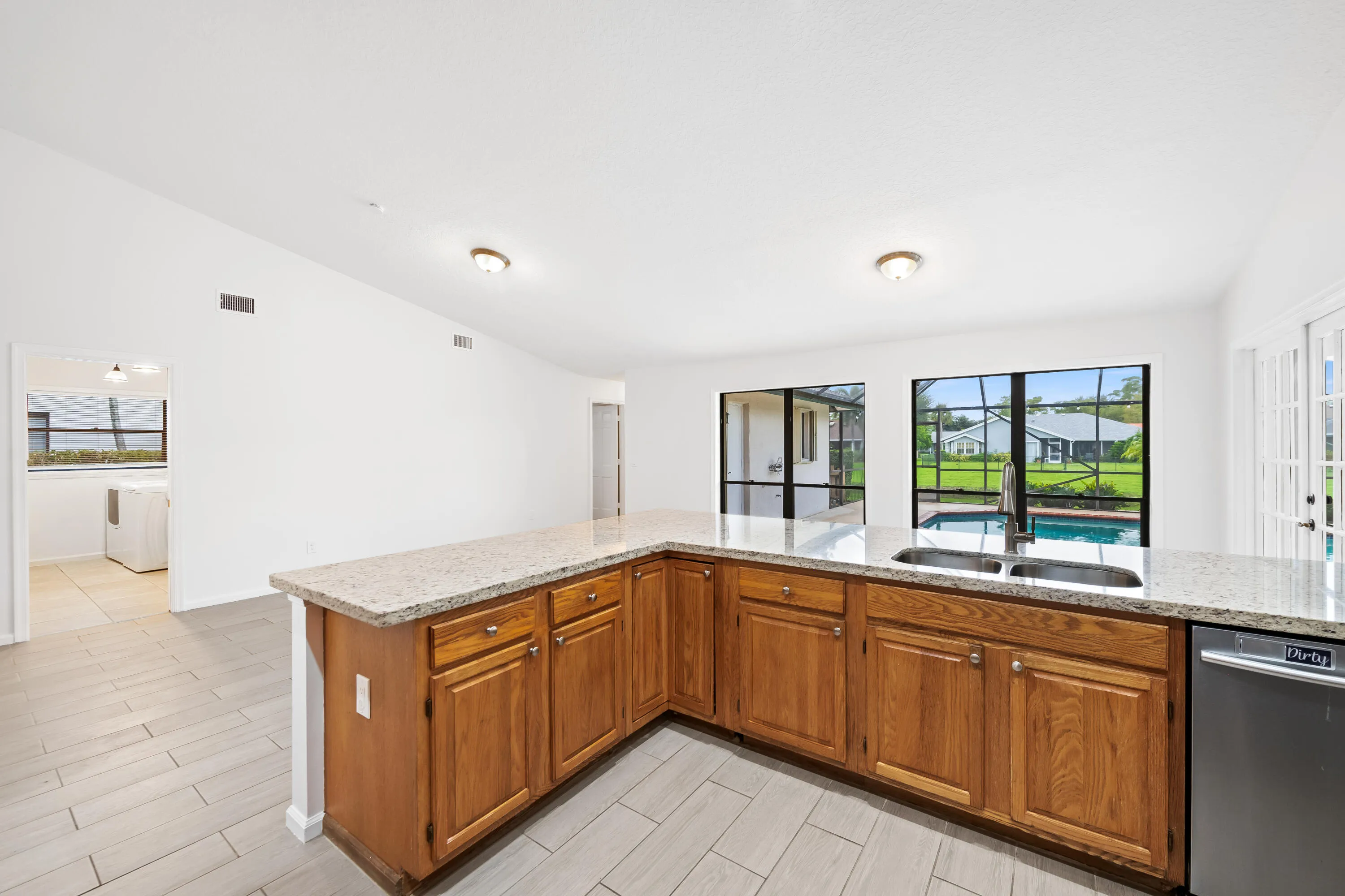Kitchen featuring wood cabinetry, light-toned countertop, dual basin sink, and tile flooring