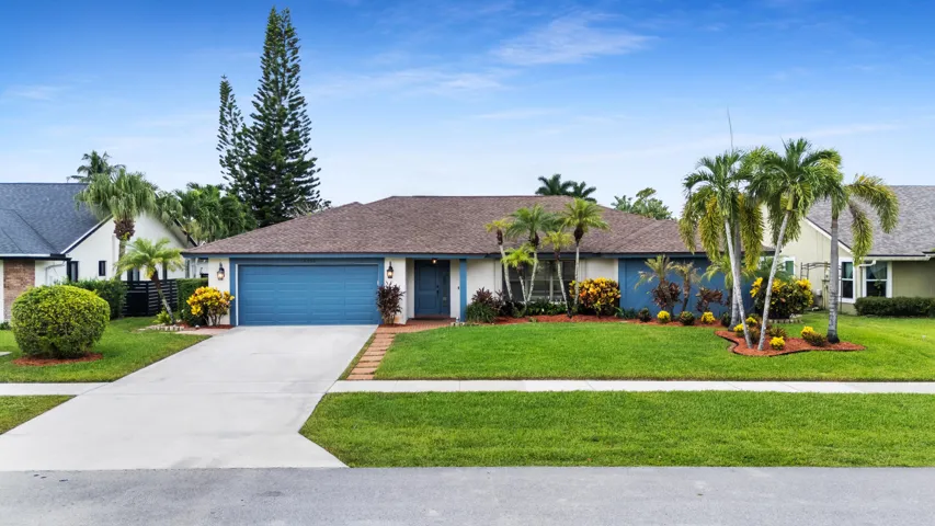 Single-story residence featuring a blue garage door, brown shingle roof, and a concrete driveway