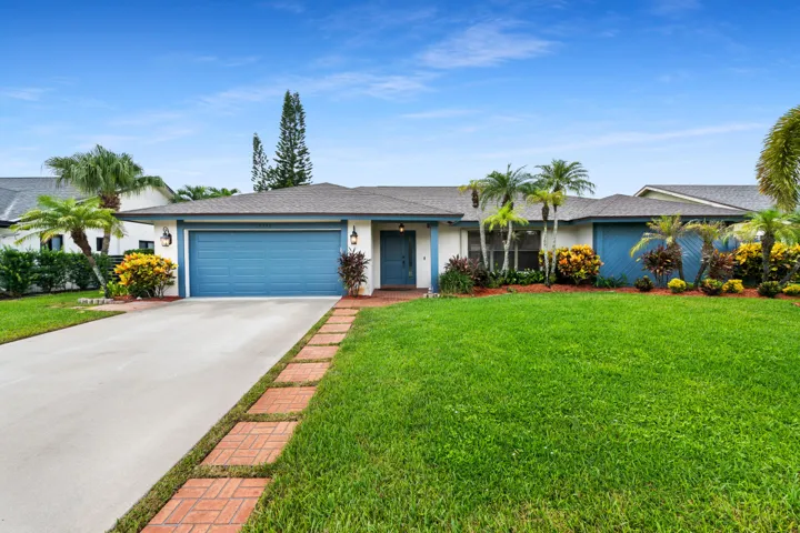 Single-story residence with a light-colored facade, blue garage door, and a gray shingle roof