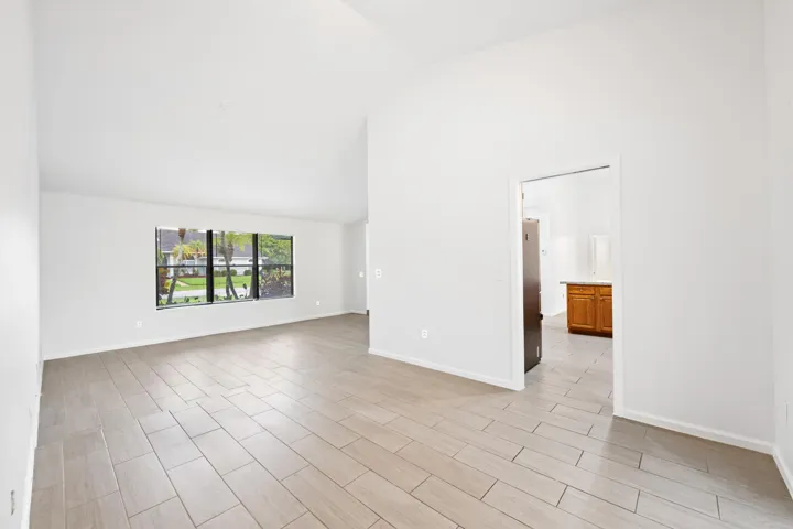 Vaulted ceilings, large window, wood-look tile flooring, and a bright, neutral color palette