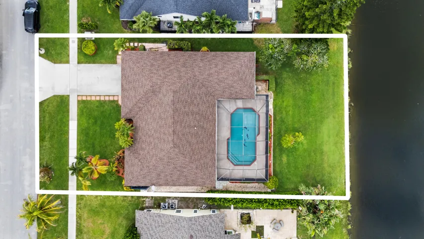 Property featuring a private swimming pool with a screened enclosure, extensive rear lawn, and mature landscaping