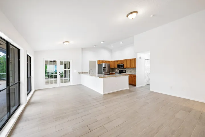 Light wood-finish flooring with an open kitchen layout featuring wood cabinetry, stainless steel appliances, and a breakfast bar