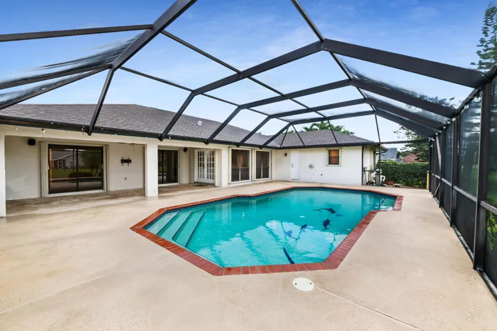 Screened pool enclosure with a geometric pool, integrated steps, and a surrounding concrete patio