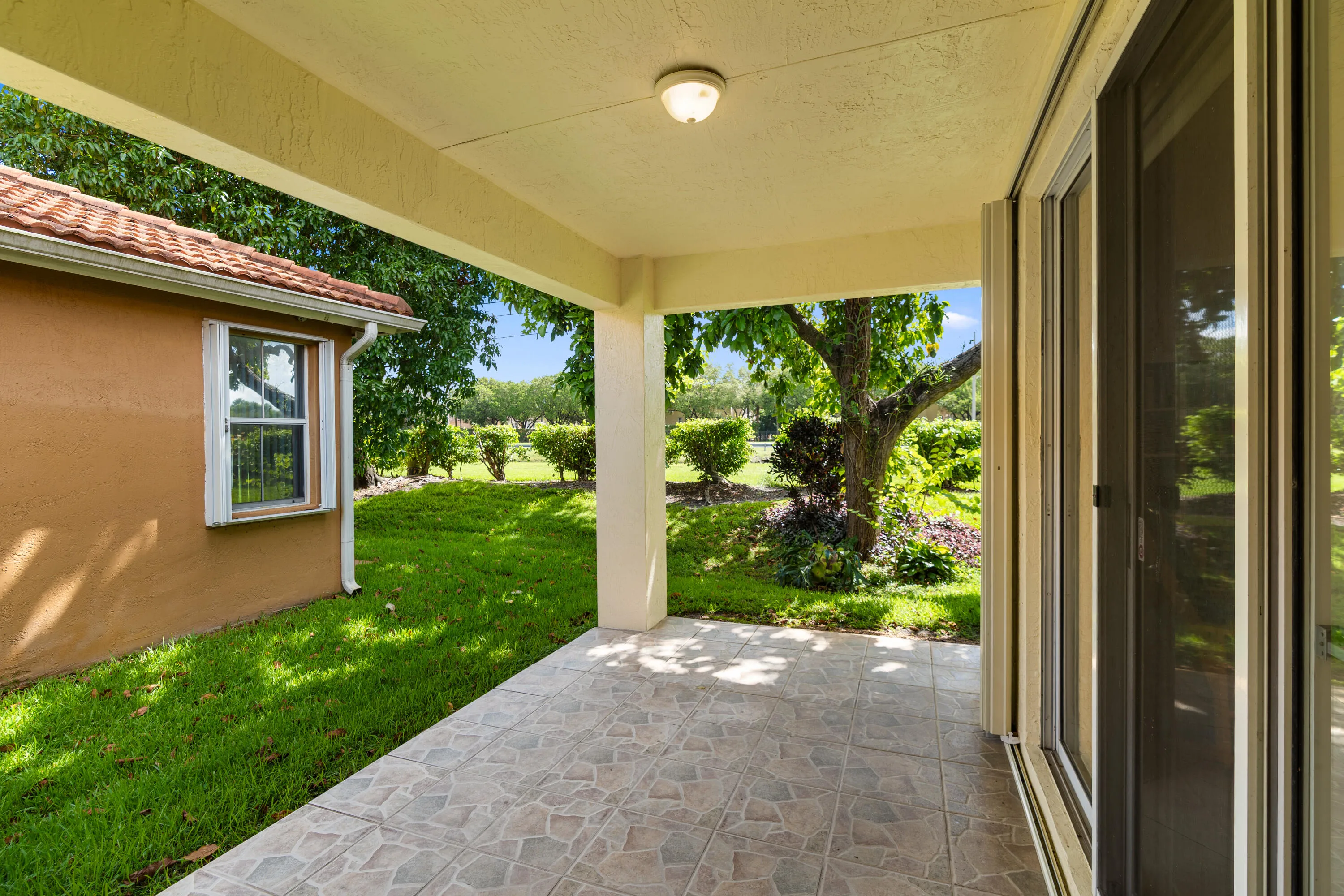 Step outside to a covered patio and peaceful backyard surrounded by mature tropical landscaping. With a berm and canal behind the property and no homes directly behind, the outdoor space offers a wonderful sense of privacy.