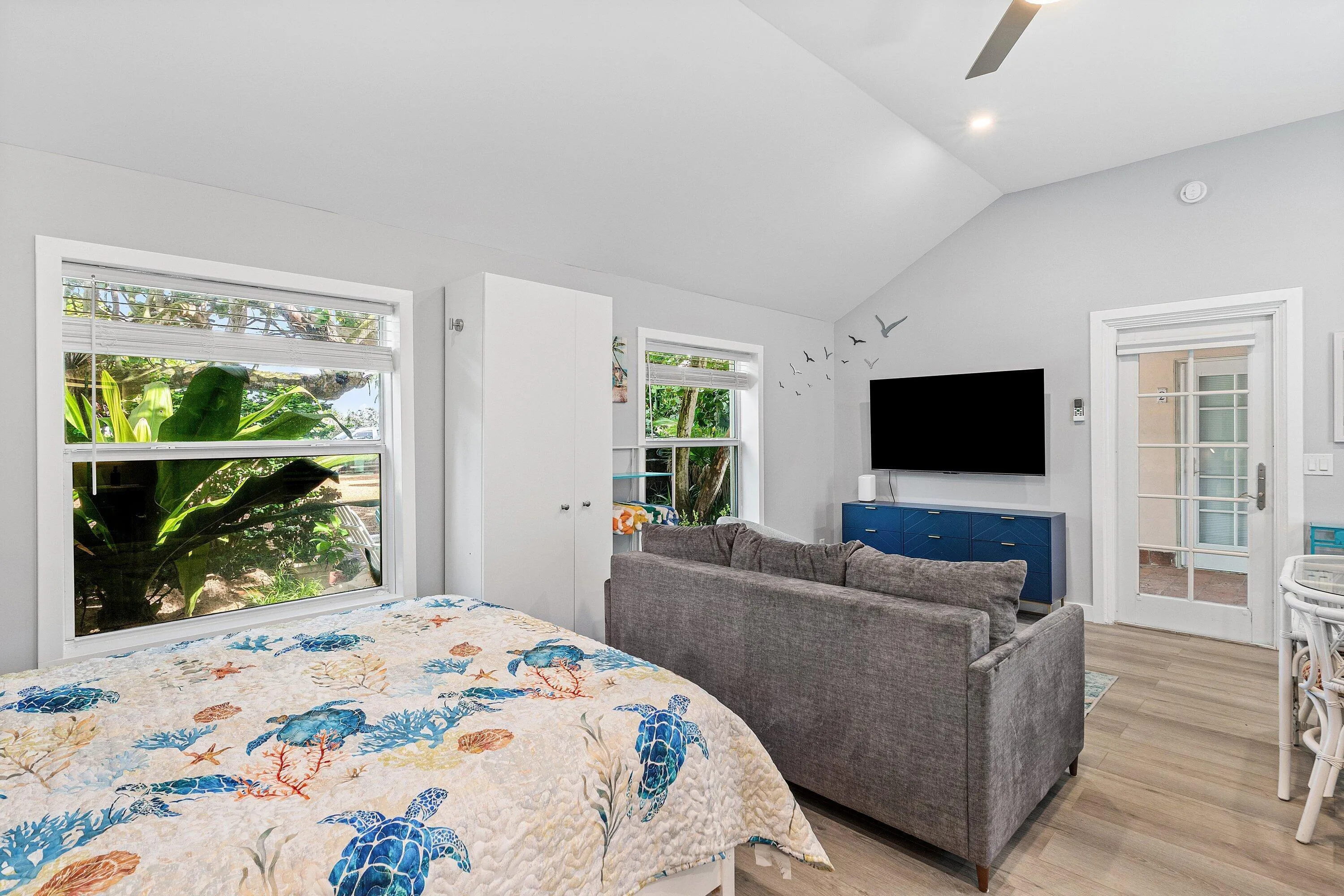 Vaulted ceiling, recessed lighting, wood-finish flooring, white double-pane windows, and a built-in storage cabinet