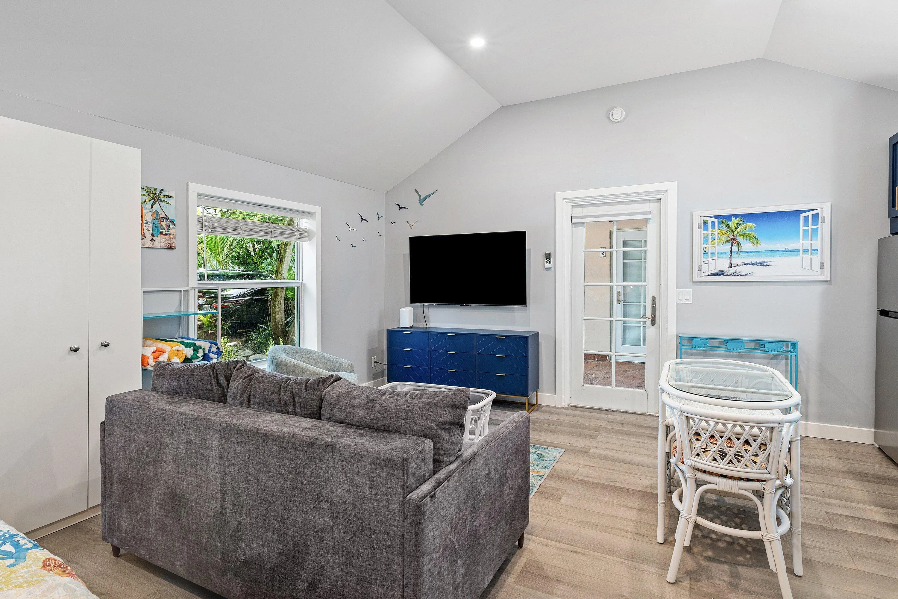 Vaulted ceiling, recessed lighting, wood-finish flooring, white built-in cabinetry, and a glass-paneled door