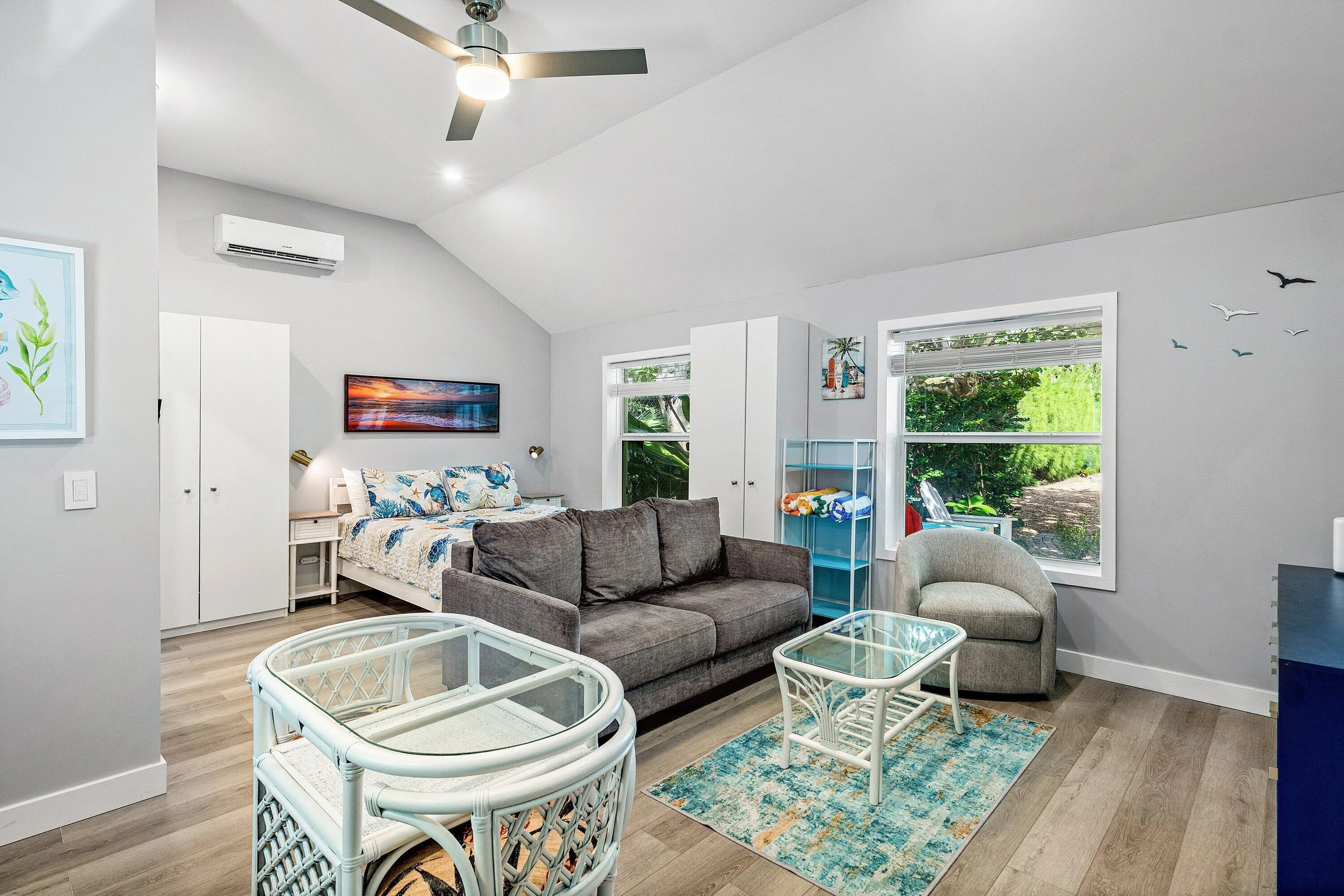 Vaulted ceiling with a ceiling fan, recessed lighting, wood-finish flooring, two large windows, and a built-in air conditioning unit