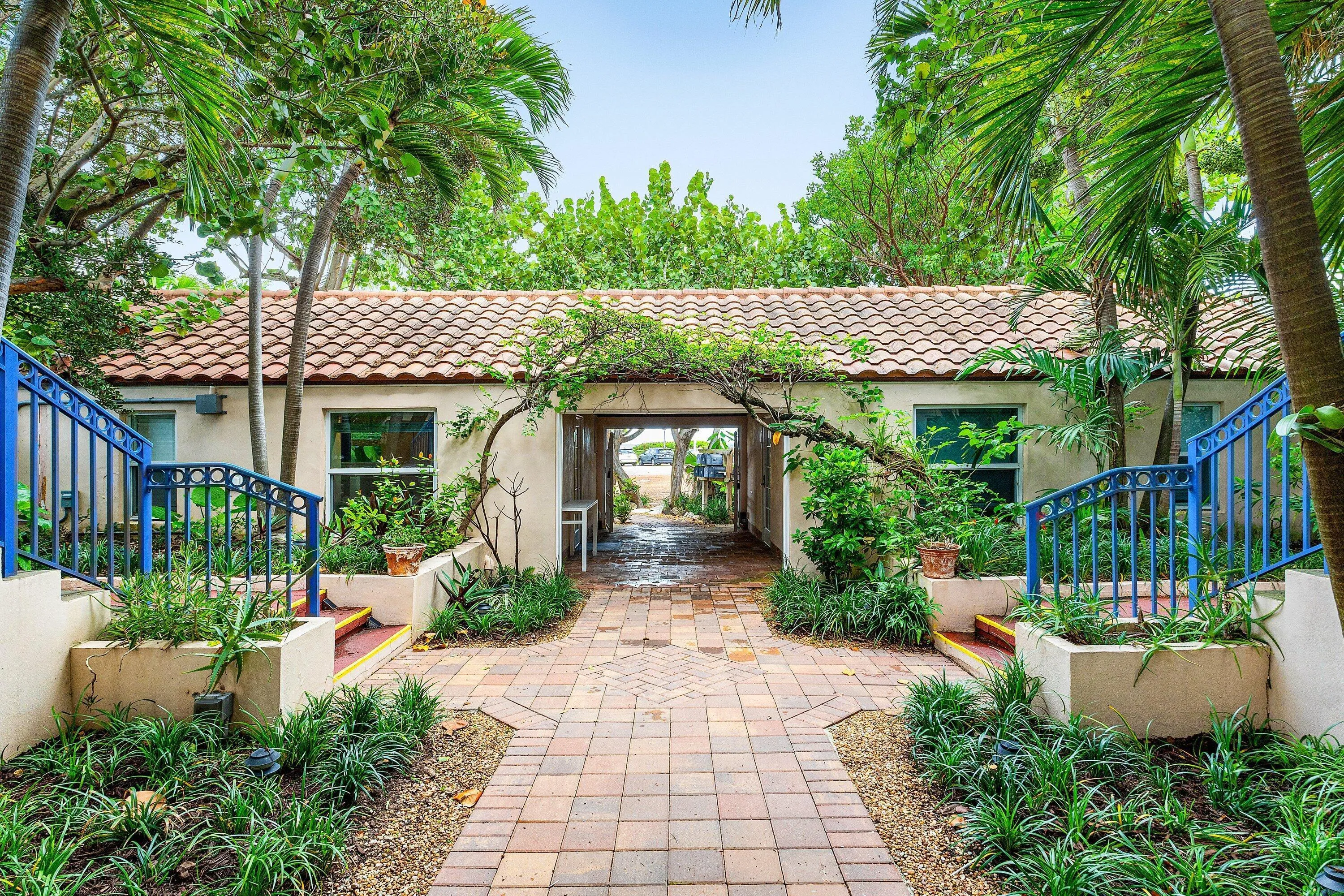 Terracotta tile roof with stucco exterior, arched breezeway, and paver pathway