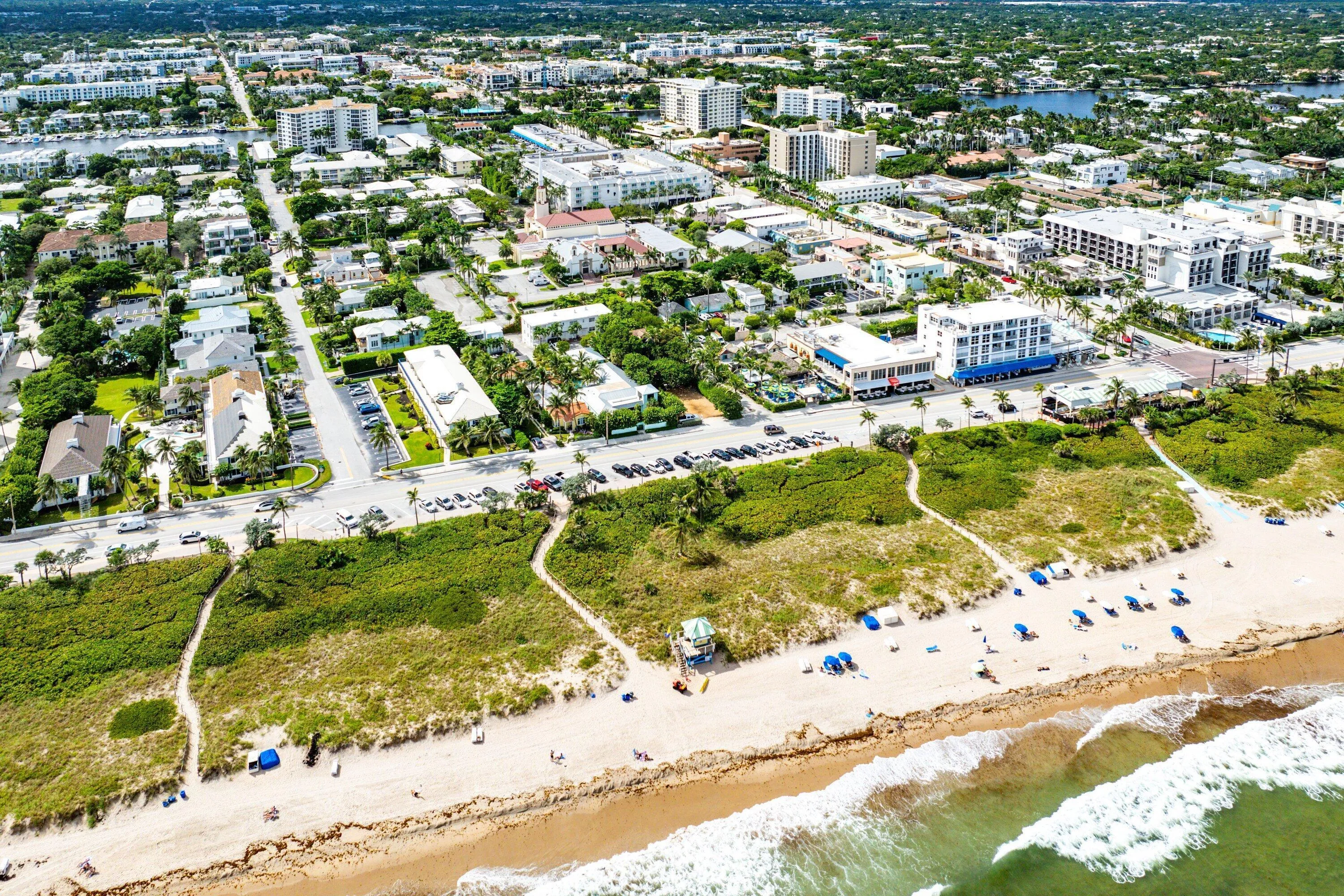 Coastal proximity with beachfront access, established urban development, and lush green landscaping