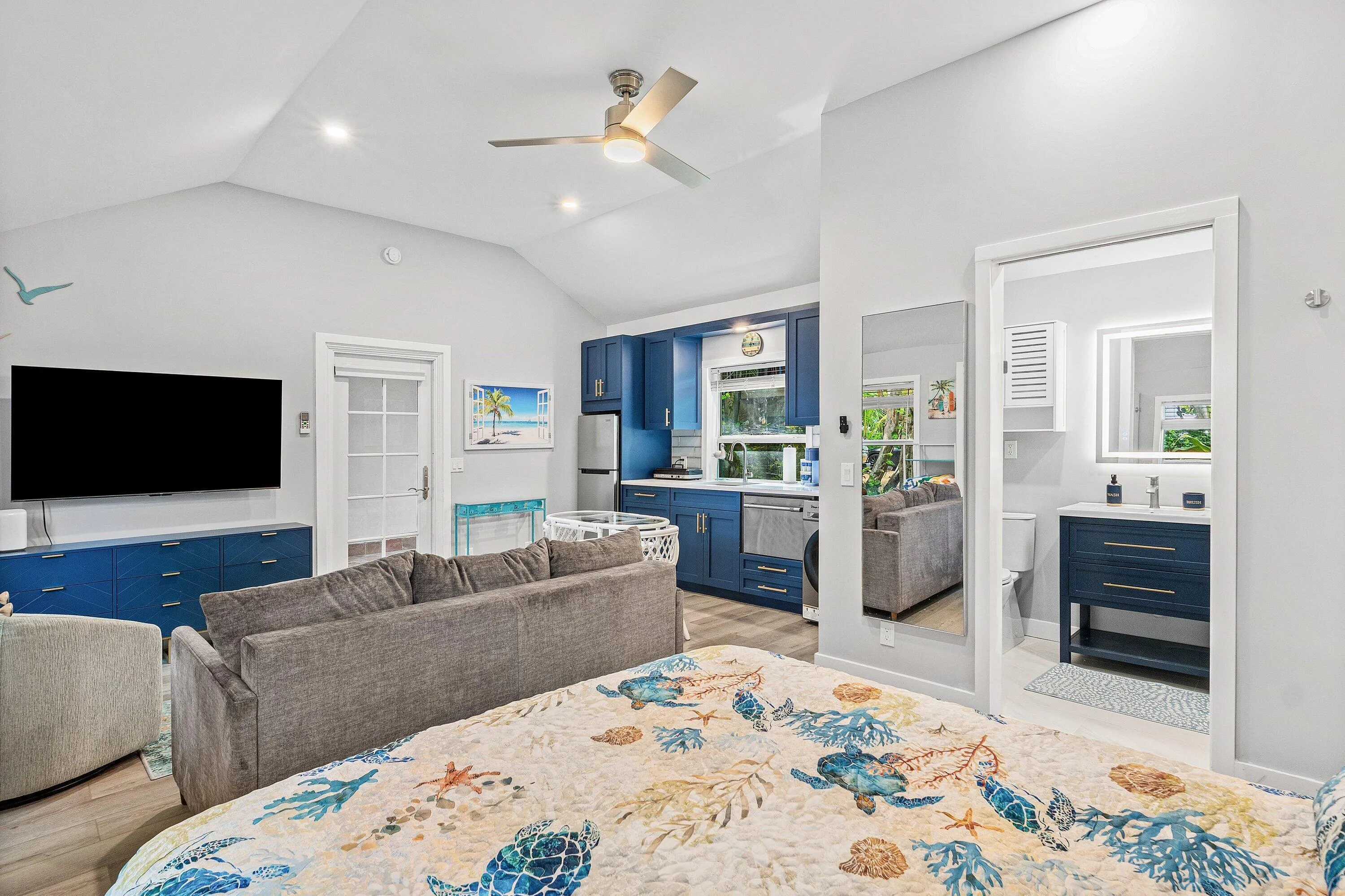 Vaulted ceiling, ceiling fan, wood-finish flooring, recessed lighting, and a built-in entertainment console