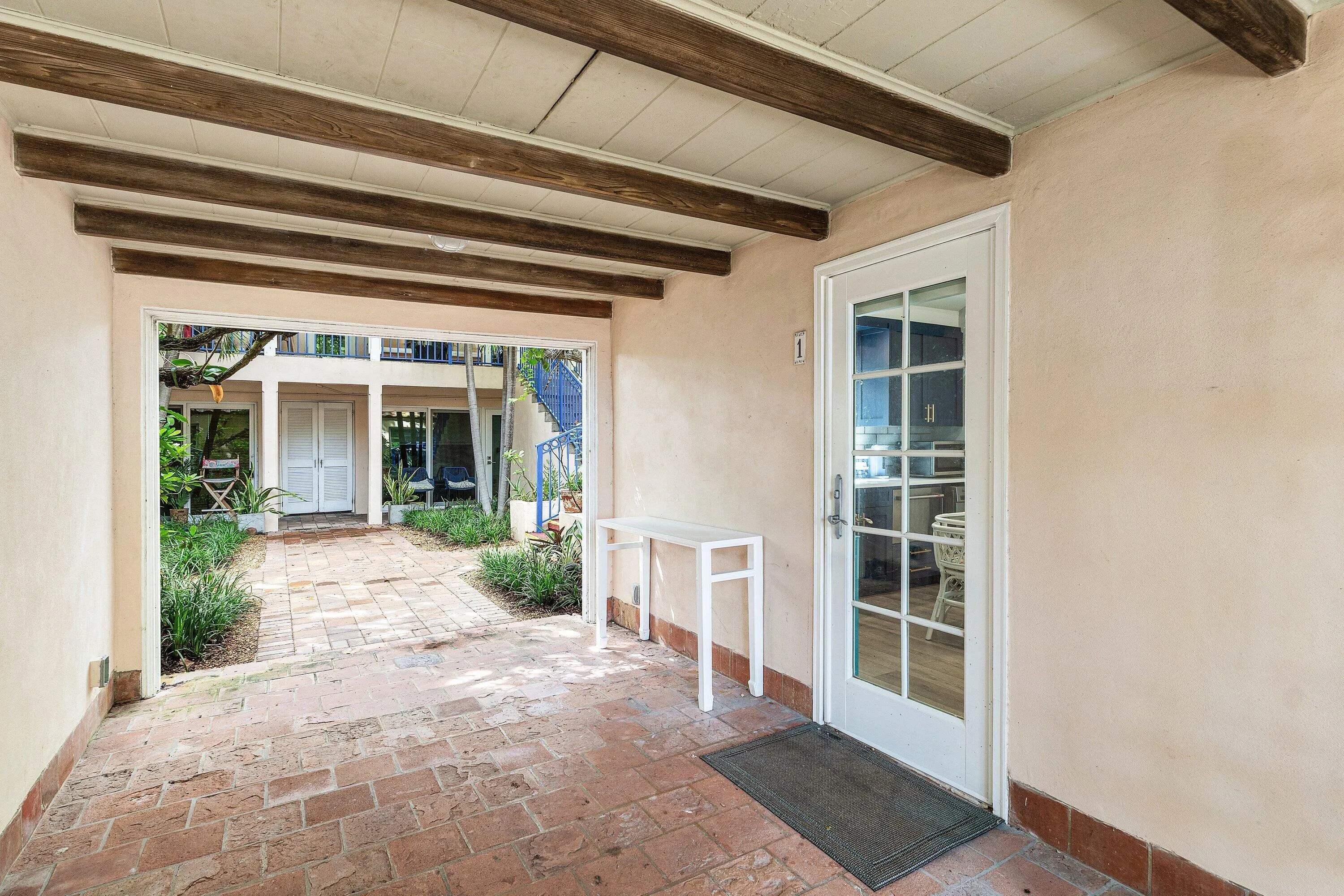 Covered entry with exposed wood ceiling beams and brick flooring