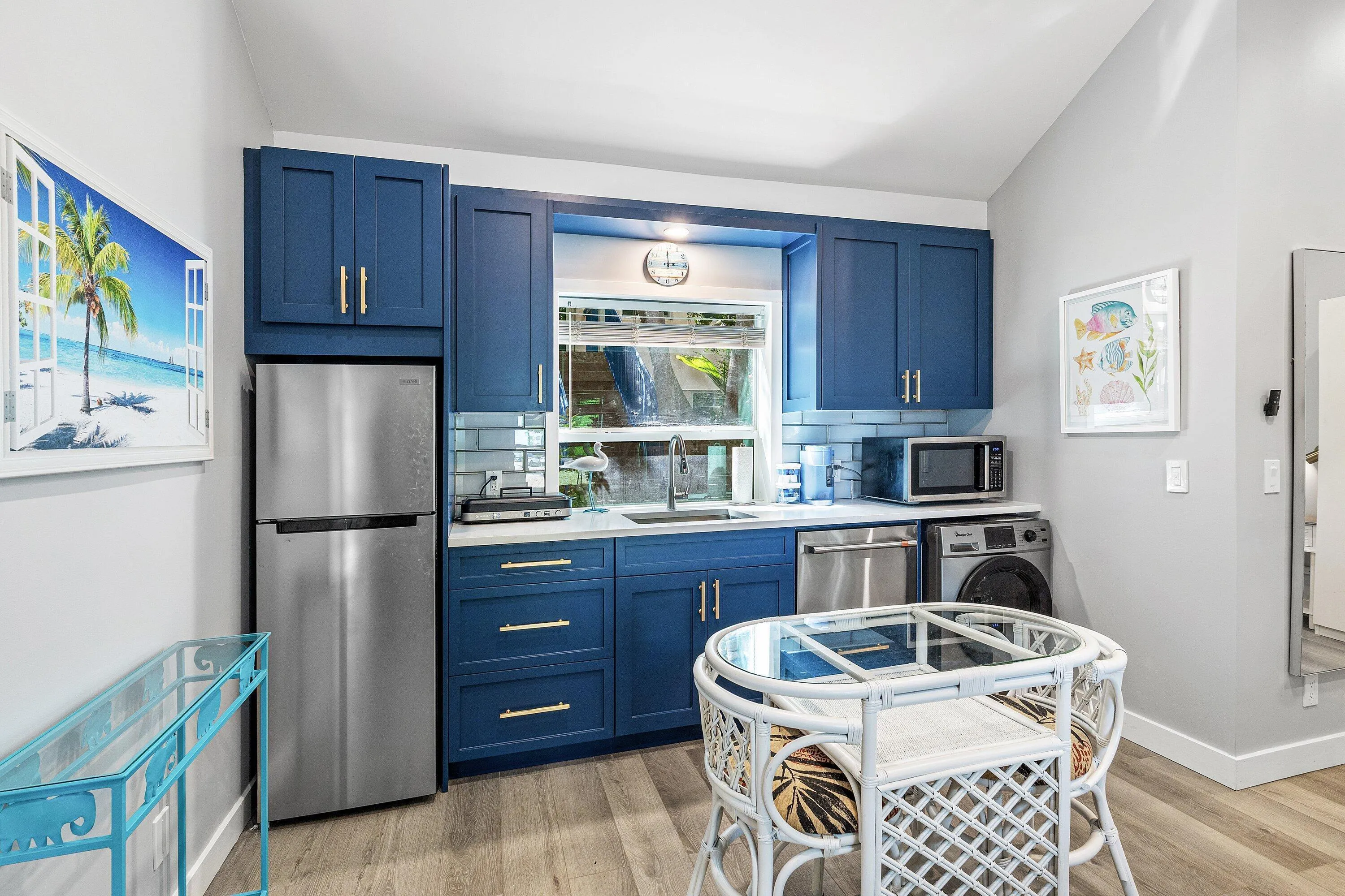 Compact kitchen featuring blue cabinetry, stainless steel appliances, a white countertop, and a tiled backsplash