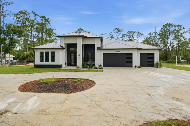 Contemporary exterior with a metal roof, two-car garage with modern doors, and a concrete driveway