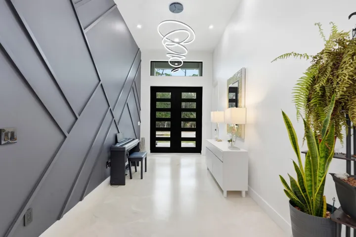 Modern entry featuring a geometric accent wall, high ceilings, recessed lighting, and a contemporary pendant fixture