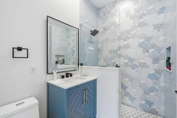 Walk-in shower with decorative wall tile, glass enclosure, and a built-in shower niche