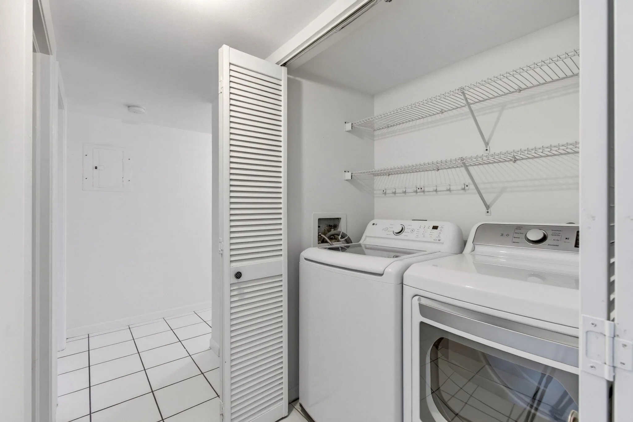 Laundry area with a louvered bi-fold door, wire shelving, and a tiled floor