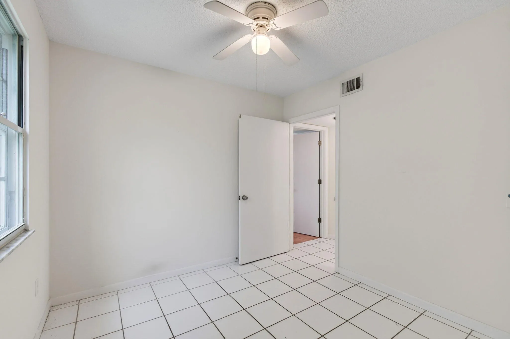 White tile flooring, a window with horizontal muntins, a ceiling fan with integrated lighting, and a white interior door