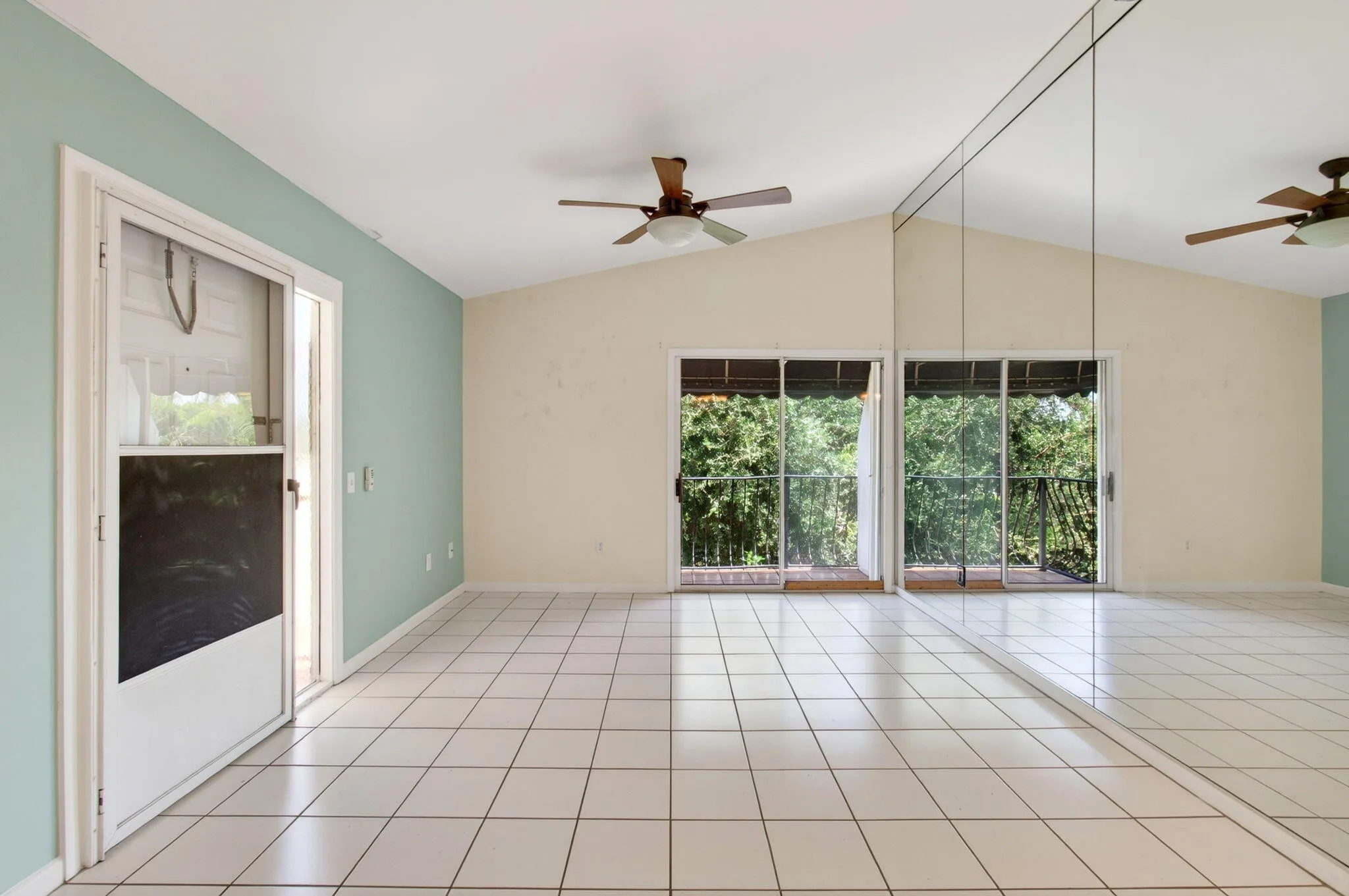 Vaulted ceilings, white tile flooring, mirrored wall, and dual ceiling fans