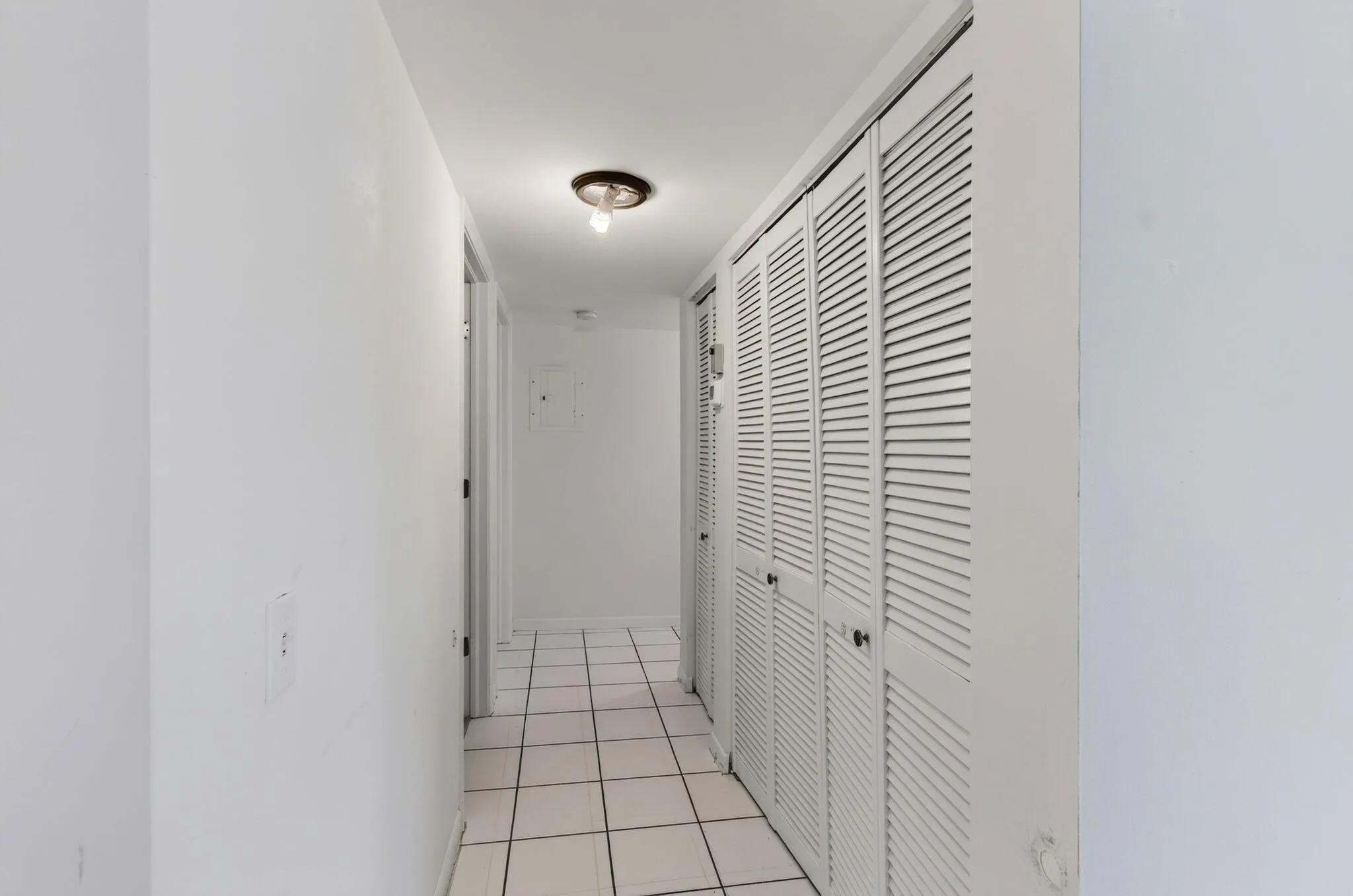Hallway featuring ceramic tile flooring, louvered bi-fold closet doors, and recessed lighting