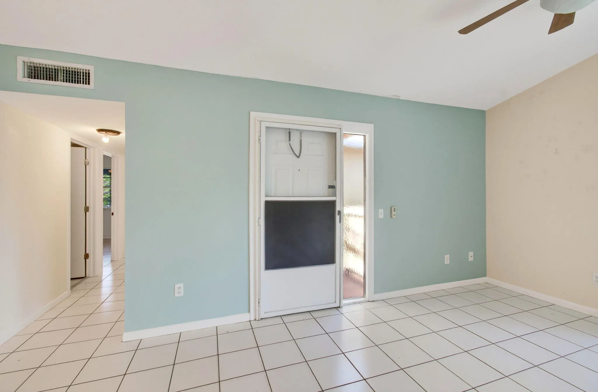 White diagonal tile flooring, sliding glass door, overhead lighting, ceiling fan, and wall-mounted air conditioning vent