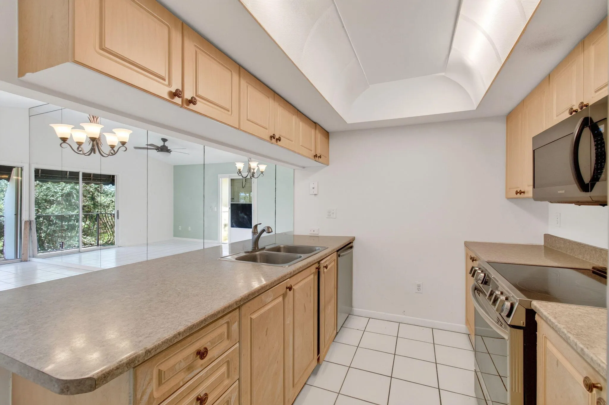 Kitchen featuring light wood-finish cabinetry, solid surface countertops, a stainless steel oven/range, and a built-in microwave