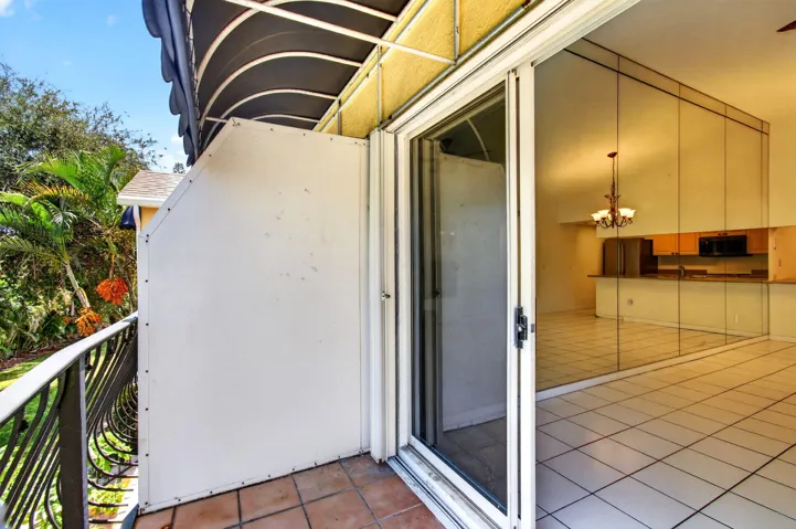 Terracotta tile balcony with wrought iron railing, awning, and sliding glass door
