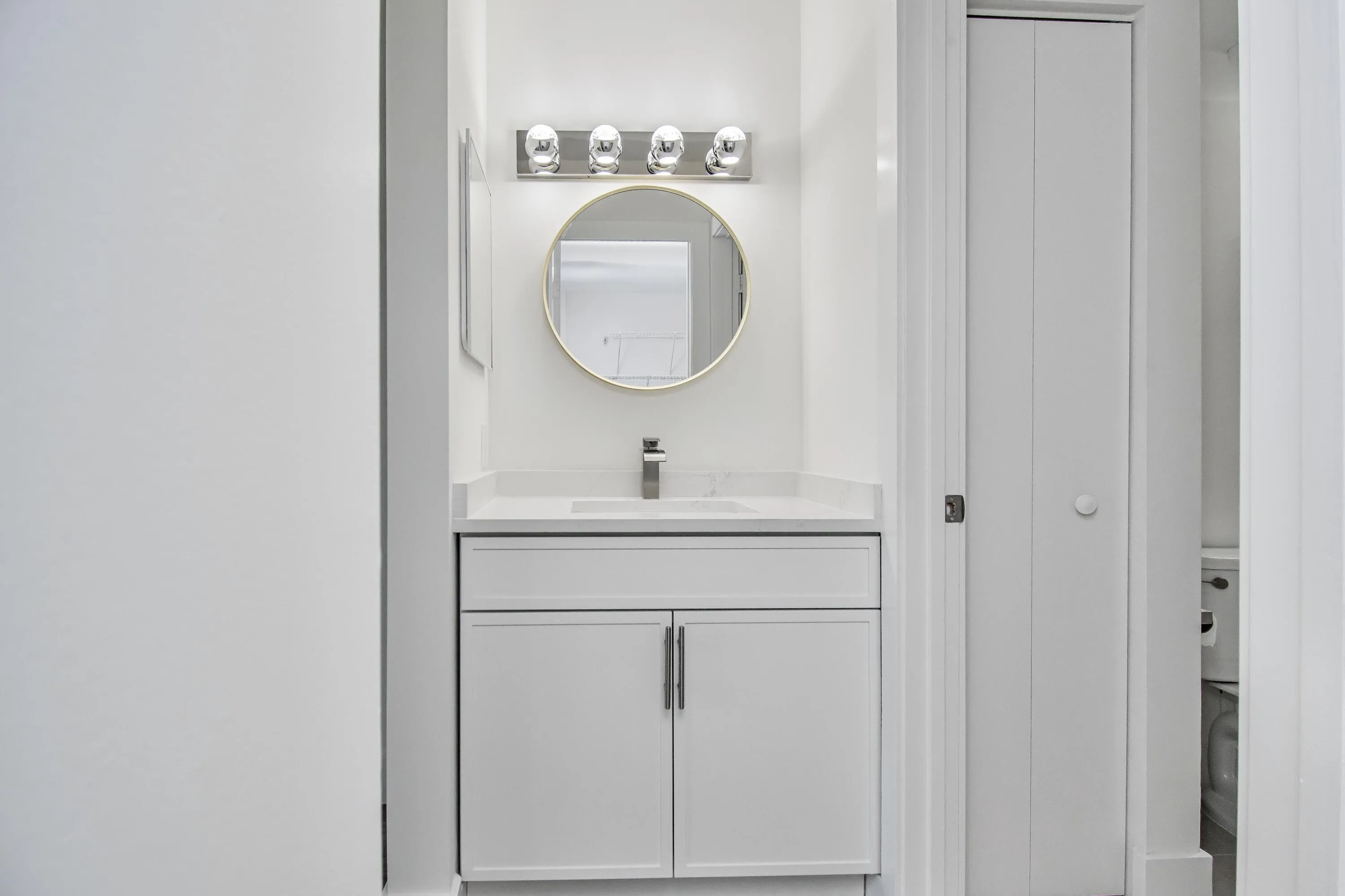 Separate dressing area vanity and integrated sink, polished chrome faucet, and round framed mirror