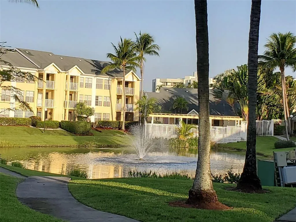 Water feature with a fountain, lush green landscaping, and mature palm trees
