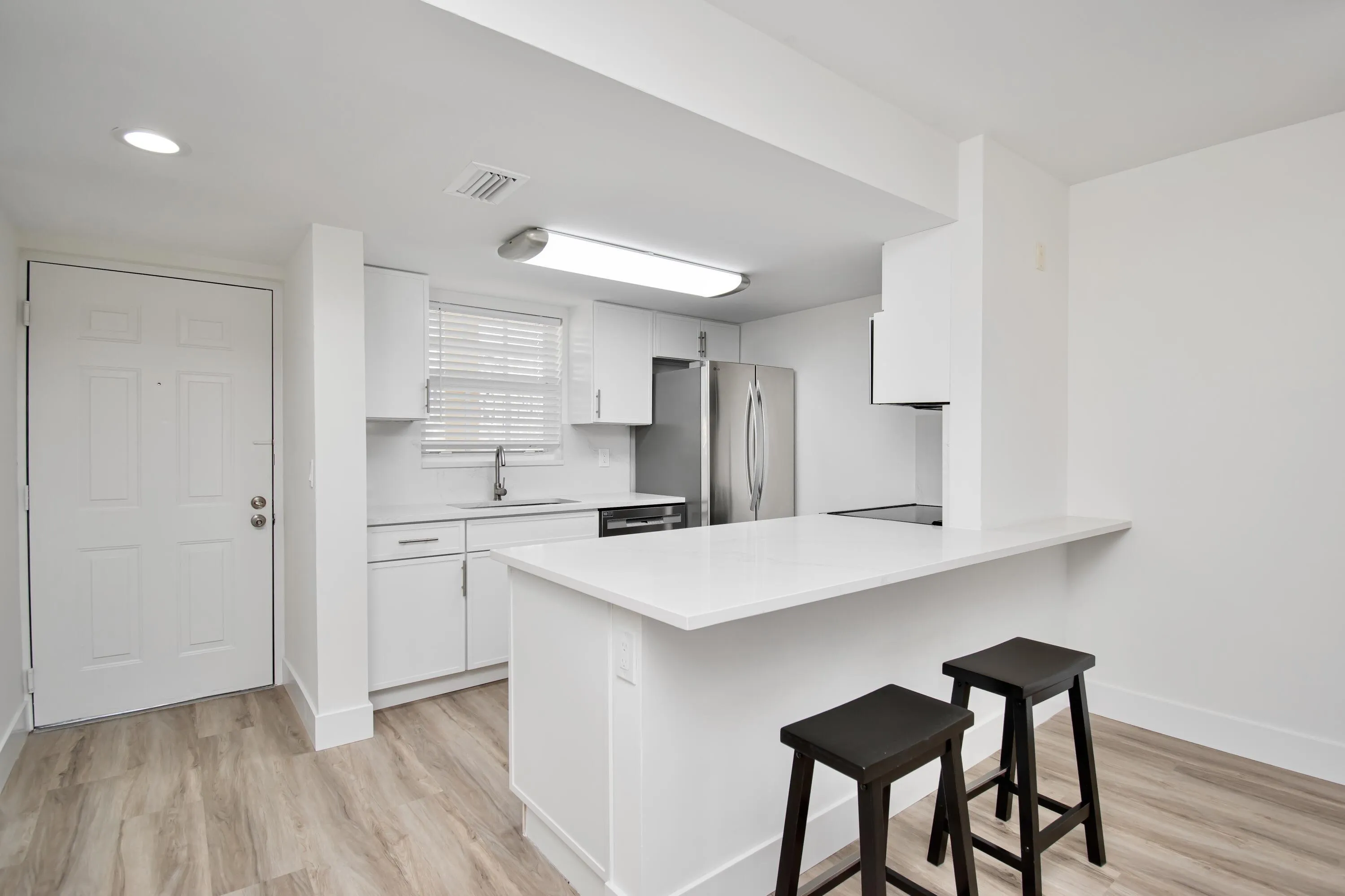 Kitchen featuring a breakfast bar, stainless steel appliances, white cabinetry, and wood-finish flooring