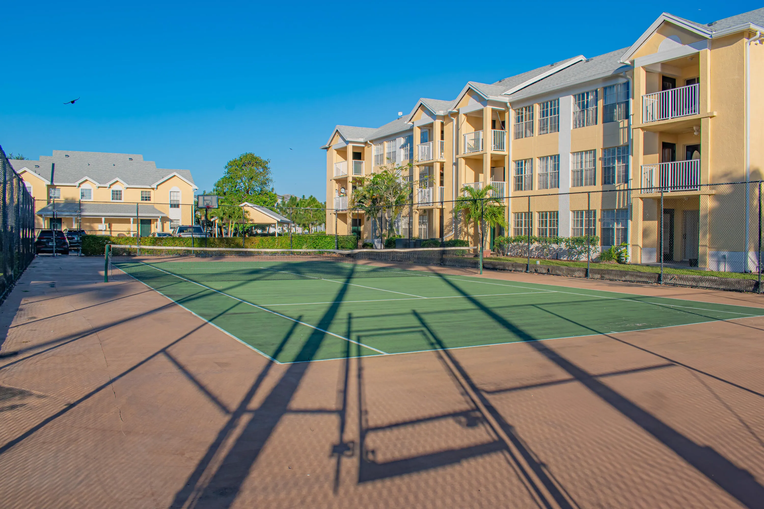 On-site tennis court with green playing surface and perimeter fencing