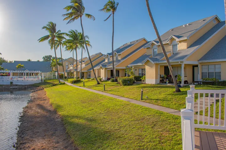 A lakeside community featuring stucco exteriors, individual patios, mature palm trees, lot's of open space.