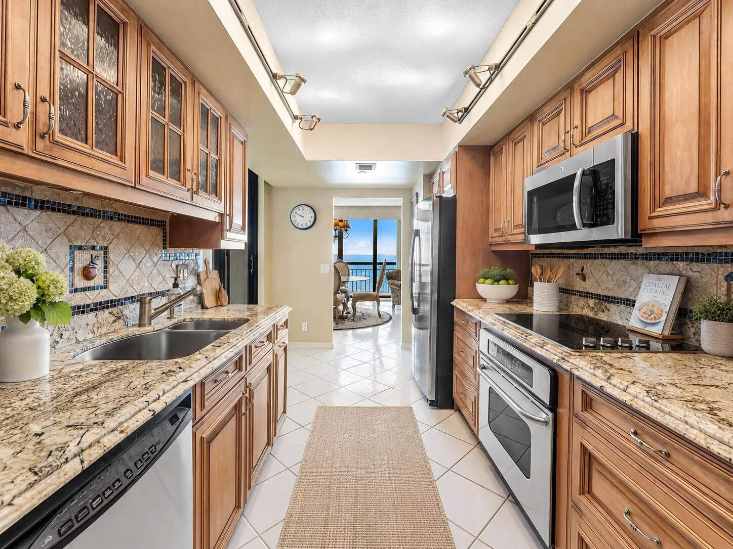 Kitchen includes abundant wood cabinetry, stone counters and backsplash, stainless appliances and extensive preparation space.